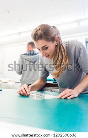 Woman preparing advertisement sticker with text to be printed on a T-Shirt