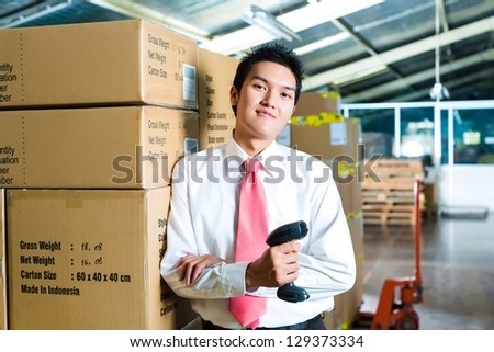 Young man in a suit with a bar code scanner in a warehouse