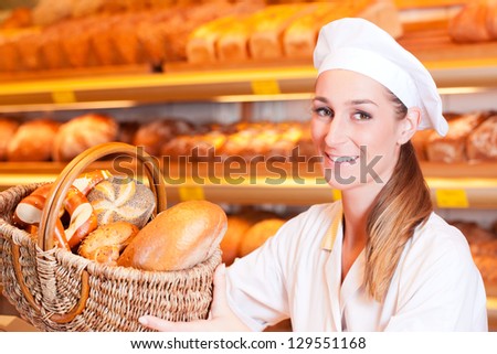 Female baker or saleswoman in her bakery with fresh pastries and bakery products