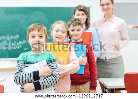 Proud students with books and teacher standing in school class