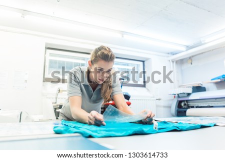 Woman flock printing a T-shirt as promotional item in workshop