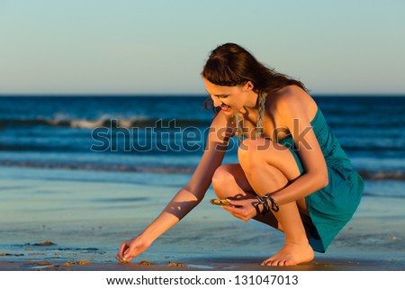 Woman looking for shells at the ocean beach in sunset