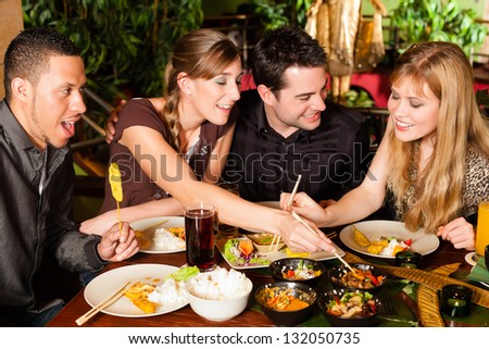 Young People Eating In A Thai Restaurant, They Eating With Chopsticks