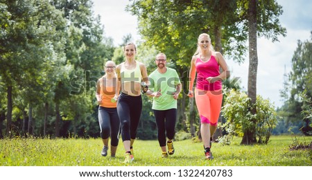 Family with personal Fitness Trainer jogging on a meadow