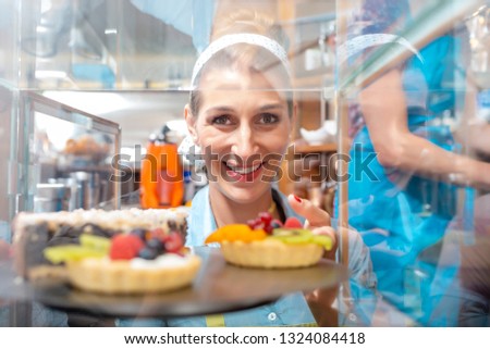 Close-up of a smiling ,id-adult woman holding sweet food in shop
