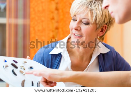 Older woman or female pensioner with a hearing problem make a hearing test and may need a hearing aid, she looking on a selection of them