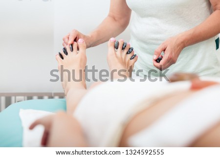 Masseuse placing stones in middle of legs finger in spa