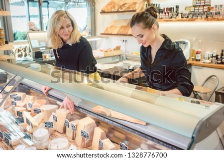 Shop clerk women at the cheese counter in a supermarket working