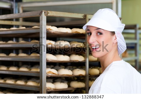 Female baker baking fresh bread rolls in the bakehouse