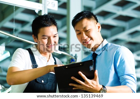 Worker or production manager and owner, ceo or controller, look on a Clipboard in a factory