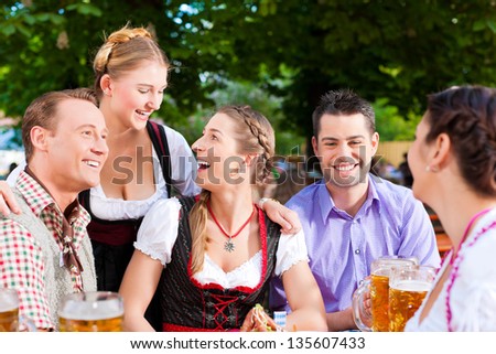 In Beer garden - friends Tracht, Dirndl and on a table with beer and snacks in Bavaria, Germany