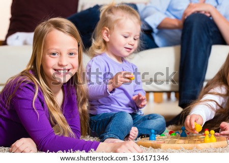 Family playing board game ludo at home on the floor