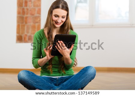 Online Dating - young woman sitting at home on the floor and buying new furniture over the Internet using a tablet computer