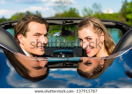 Young hip couple - man and woman - with cabriolet convertible car in summer on a day trip