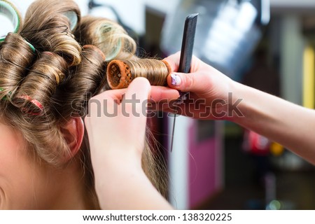 Hairdresser - hair stylist curling hairs, a female customer gets a haircut
