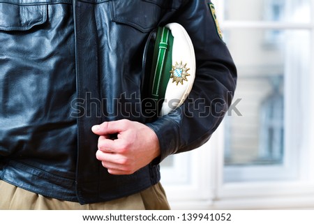 Police officer in police station, wearing his uniform with leather jacket and hat, he is ready for operation