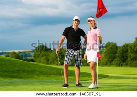 Young sportive couple playing golf on a golf course, they certainly do exercise or have training