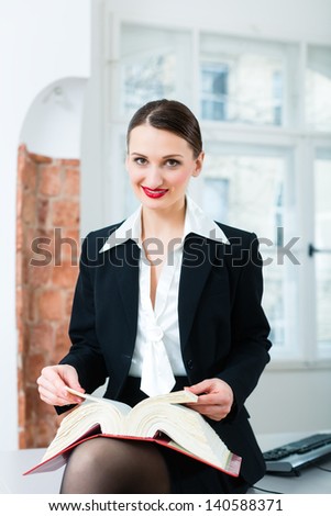 Young female lawyer working in her office reading in a typical law book