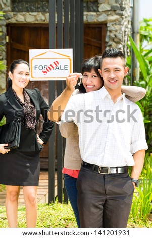 Real estate market - young Indonesian couple looking for real estate apartment or house to rent or buy, the woman holding the keys