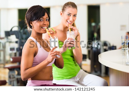 Young People - women in the gym drinking a isotonic drink or protein shake