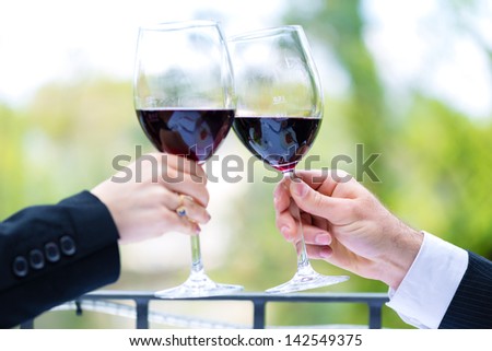 Clink with red wine glasses outside on the terrace in a fine dining restaurant