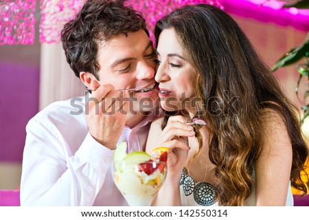 Young Couple in a Cafe or Ice cream parlor, eating an ice cream sundae together