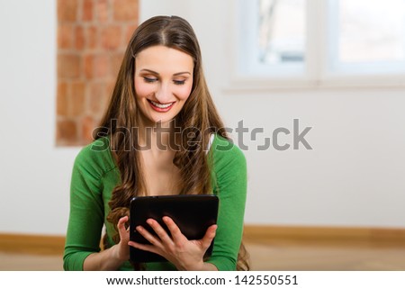 Online Dating - young woman sitting at home on the floor and buying new furniture over the Internet using a tablet computer