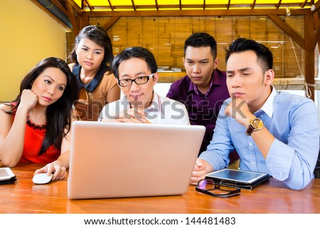 Asian Creative business agency - team meeting in an office with laptop