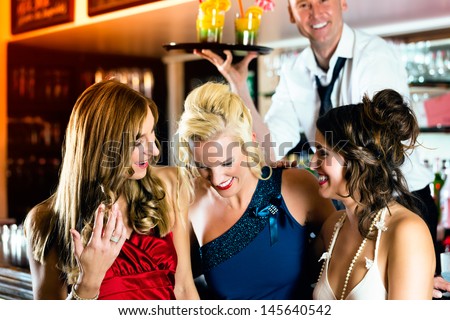 Young women in bar or club having fun and laughing, the bartender serve cocktails