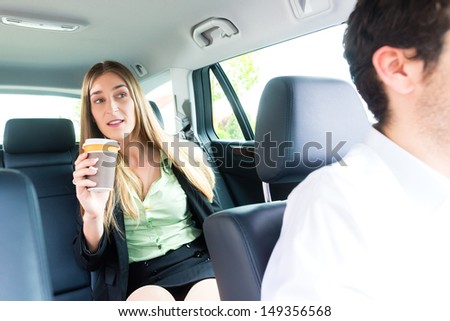 Young businesswoman traveling in taxi, she is holding cup of coffee
