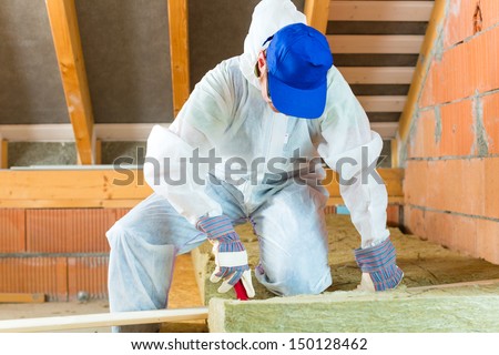 Worker In Overall Is Cutting Insulating Material With Gloves And Knife