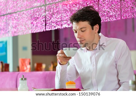 Young man in a cafe or ice cream parlor eating a cake, maybe he is single or waiting for someone