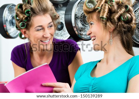 women at the hairdresser reading a magazine or a rag and chit-chat, while your hair drying under a hairdryer