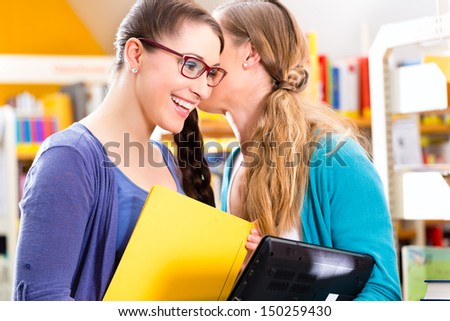 Students - Young women in library with laptop and book learning in group