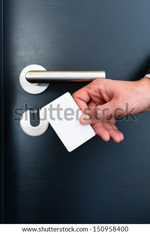 Hotel door - Young man holding a keycard in front of the electronic sensor of a room door