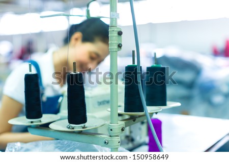 Asian Seamstress or worker in a Indonesian factory sewing with a industrial sewing machine, she is very accurate