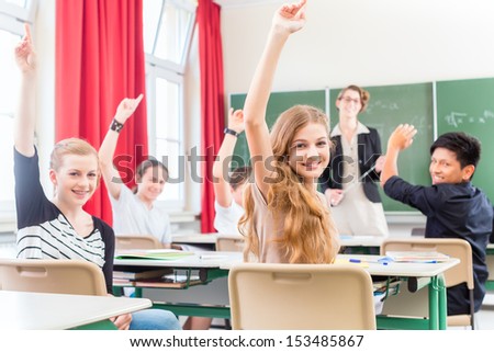 Teacher standing  in front of a blackboard or teaching students or pupils or mates, in a school class