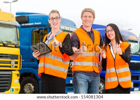 Logistics - proud driver or forwarder and colleagues with tablet computer, in front of trucks and trailers, on a transshipment point, its a good and successful team