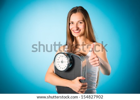 Diet and loosing weight, young woman with a scale, she is happy about the success