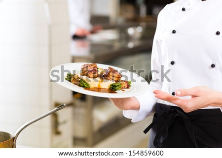 Female Chef in hotel or restaurant kitchen cooking, only hands to be seen, she is presenting a dish