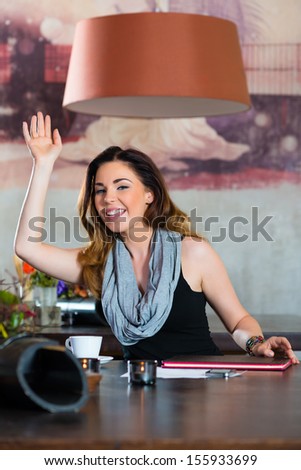 Young woman in a cafe or restaurant, she beckons to someone, perhaps she would like to pay the Bill