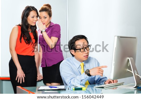 Asian Women or employee s tattle or whisper about colleague or man, bullying him in the office