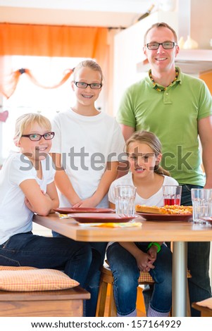 Family, father and children or daughter with friends in the kitchen at the table eating healthy fruits