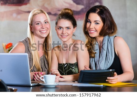 Young women or colleagues working in a cafe or restaurant, on some documents or contract with Laptop and Tablet Computer