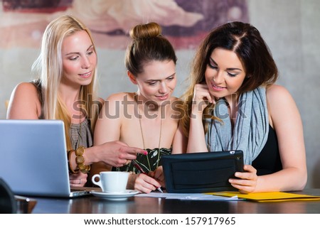 Young women or colleagues working in a cafe or restaurant, on some documents or contract with Laptop and Tablet Computer
