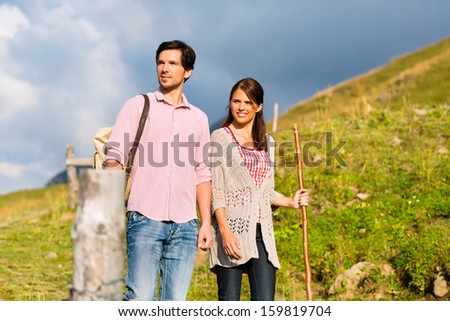 couple of man and woman hiking on mountain summit or alpine grassland in the Bavarian Alps, enjoys the panorama in the leisure time or in vacation