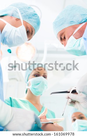 Hospital - surgery team in operating room or Op of a clinic operating on a patient in an emergency situation