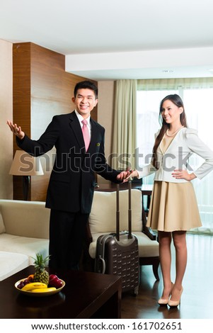Asian Chinese Hotel Manager or director or supervisor presenting arriving VIP guests the room or suite