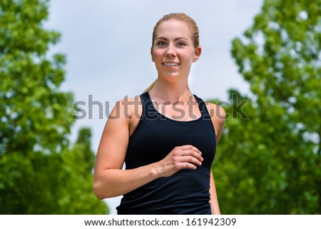 Urban sports - woman running for better fitness in the city park on a cloudy summer day