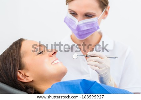 Female patient with dentist in a dental treatment, wearing masks and gloves
